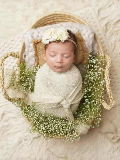 An overhead shot of a newborn swaddled in a basket filled with baby's breath. This composition creates a beautiful, nest-like effect, emphasizing how new and precious she is.