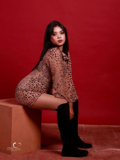 A confident seated pose that showcases the full outfit. The composition is balanced, and her expression is strong and steady.