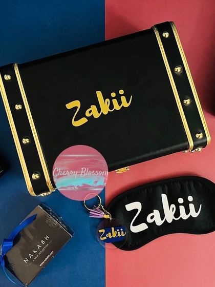 A flat-lay of our customised birthday hamper for men. The personalised trunk box, eye mask, sipper, and keychain are displayed alongside the grooming products included in the gift.