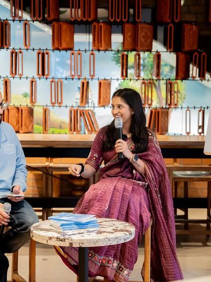 Author Pooja Jain speaks about "The Wheel of Life," demonstrating the typical setup for our author interview sessions in a cafe environment.