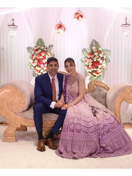 A formal portrait of a couple seated on an elegant chaise lounge at their engagement reception.