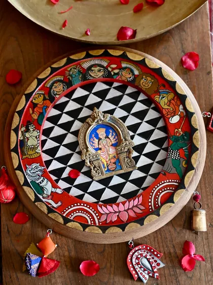 A hand-painted homage to the goddess Durga, housed within a restored vintage clock frame and a salvaged brass Prabhavali. This piece is inspired by the protective spirit of a dreamcatcher and the narrative style of Pattachitra art, adorned with found-object trims to complete its story.