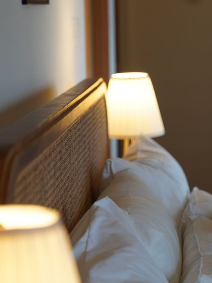 A close-up of a rattan headboard, its warm texture glowing in the lamplight. This is what I call 'Rattan Grace'.