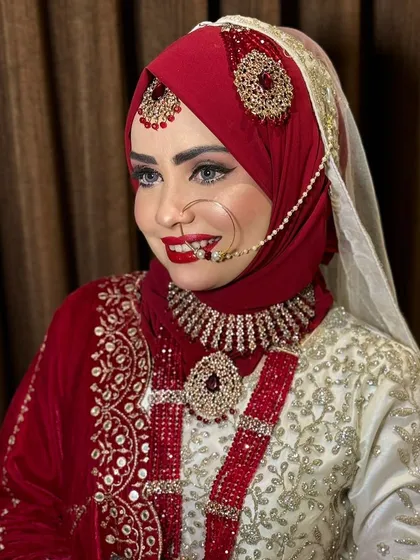 A radiant and happy Hijabi bride. The red and white color combination of her outfit is classic, and the makeup enhances her joyful expression.