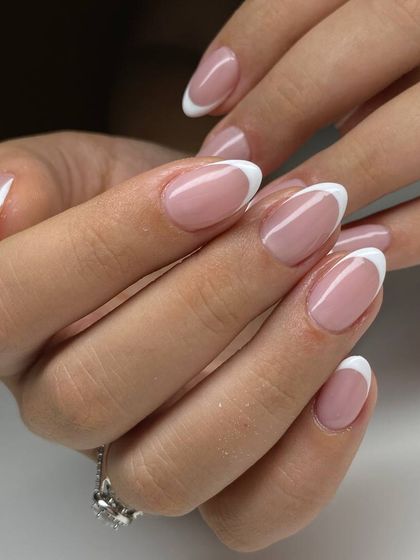 A classic French manicure on beautifully shaped oval nails. The crisp white tip and sheer pink base create a look of timeless elegance.