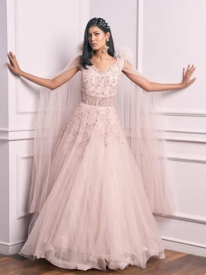 A full-length view of our fairytale pale pink gown with a feather-detailed cape.