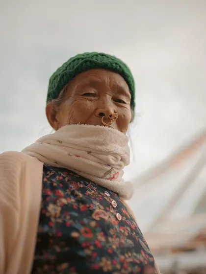 A low-angle portrait of an elderly woman in Kathmandu. Her warm smile and the traditional nose ring are the focus of this intimate shot.