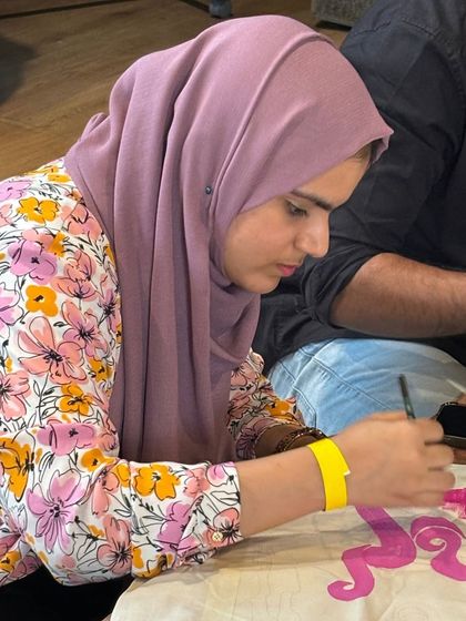 Another participant deeply engaged in painting her tote bag design. Private parties are a great way to get personalized guidance.