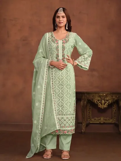 A light green organza suit with beautiful white thread embroidery. The bell sleeves and delicate lacework add a touch of vintage charm.