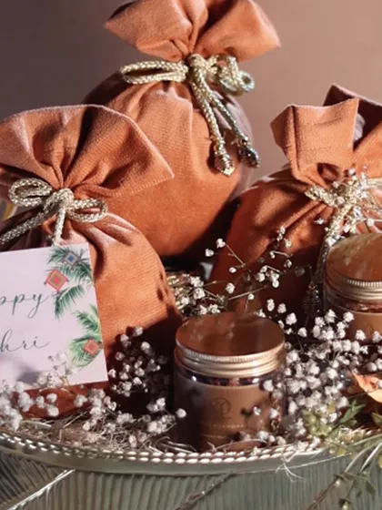 A close-up of the gourmet treats and velvet potlis from our Lohri hamper, arranged on a silver-plated tray. The "Happy Lohri" card adds a personal touch to this sweet gesture.