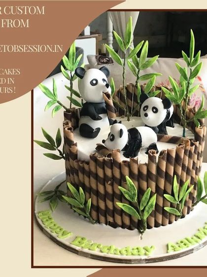 An adorable panda-themed cake surrounded by chocolate wafer sticks as bamboo, with cute fondant pandas playing among the leaves.