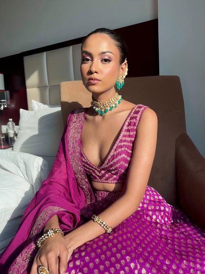 A sun-kissed shot of a stunning Mehendi look. The purple tones in the eyeshadow pick up the color of her Sawan Gandhi lehenga, while the skin is kept fresh and glowing.