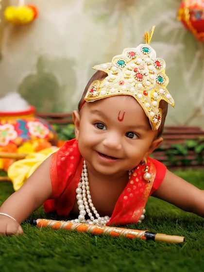 An absolutely heart-melting smile from a baby Krishna, lying on his tummy with his flute.
