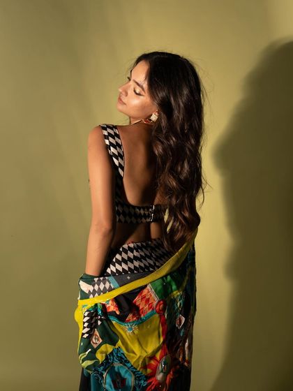 A back-facing pose that highlights the open-back design of the top and the flow of her hair.