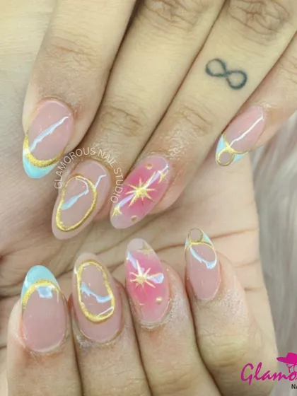 A celestial dream on your fingertips. This artistic set features a mix of pastel blue tips, gold outlines, and accent nails with a pink base and a golden starburst.