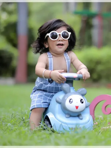 A happy toddler enjoying a ride on his toy car in the park. Outdoor shoots are perfect for active kids who love to move and play.