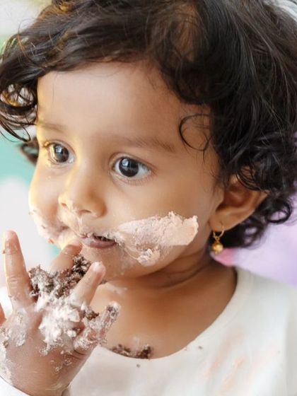A detailed close-up of the birthday girl tasting the frosting from her fingers, a perfect capture of sensory exploration.