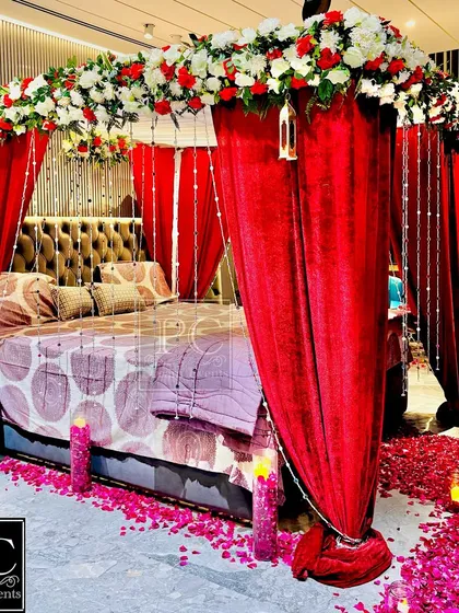 Another angle of the romantic room setup, showing the beautiful details of the floral canopy and hanging crystal strings. The warm glow of candles adds to the intimate atmosphere.