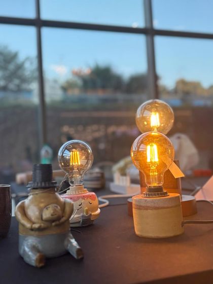 A collection of finished lamps from our workshop, glowing on a table. Each one is a testament to the unique style and creativity of the person who made it.