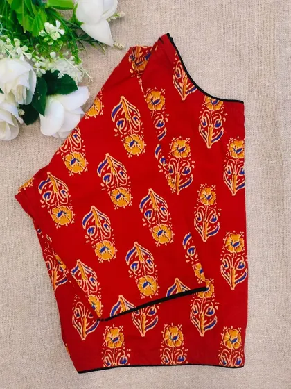 A red cotton boatneck blouse with a traditional paisley-like motif.