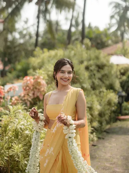 A close-up portrait of the bride, holding her floral kaleeras and smiling brightly.