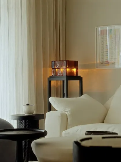 An amber glass table lamp casts a warm, inviting glow in this corner of Apartment O2. We use accent lighting to create cozy nooks and add layers of warmth to a space.