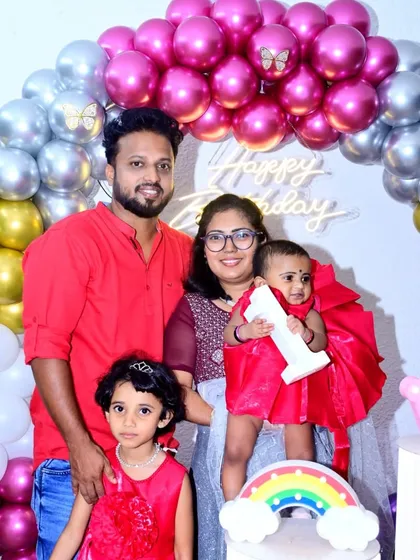 Getting a great family portrait is a key part of any celebration. Here, the family poses together during their daughter's first birthday, with the themed balloon arch creating a perfect backdrop for a sharp, well-lit family photograph.