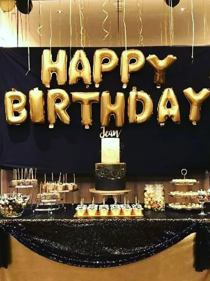 This birthday decoration in black and gold includes a backdrop and a decorated table, creating a perfect spot for the cake and desserts.