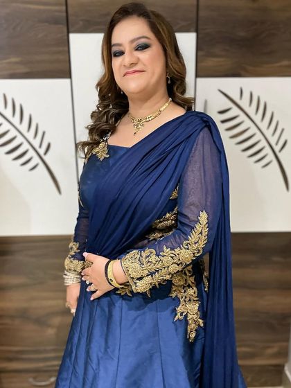 The complete look, showing how the intense smokey eye makeup is balanced by soft, flowing curls and an elegant navy blue gown with gold embroidery.