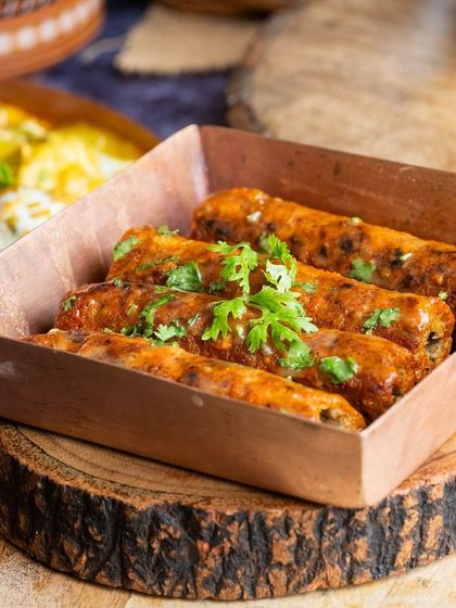 Succulent seekh kebabs served in a copper dish, showcasing the variety of cuisines featured in our pop-ups.