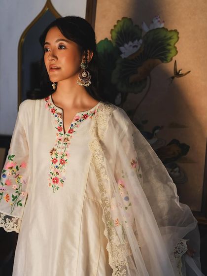 A close-up portrait for Baavli, highlighting the delicate floral embroidery on an elegant white kurta.
