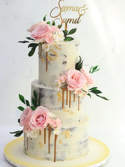 For a touch of rustic elegance, this semi-naked cake is a beautiful choice. The lightly frosted layers are adorned with a gold drip and clusters of delicate pink sugar flowers, perfect for a chic and romantic wedding.
