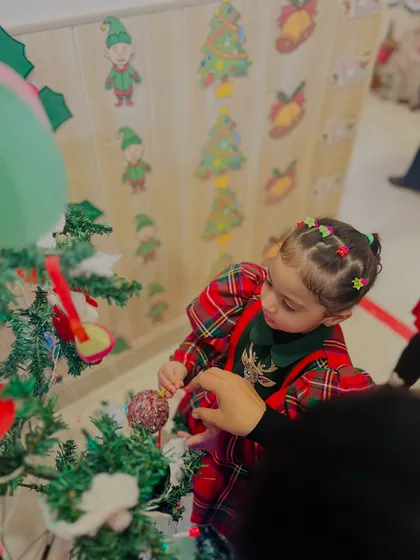 Another angle of a child decorating the tree, showing her careful placement of the ornament.