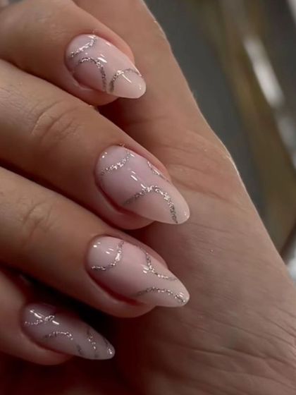 A simple yet elegant design with sheer pink nails and wavy lines of fine silver glitter for a touch of class.