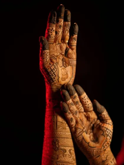 A powerful shot of bridal hands against a dark background, highlighting the intensity of the henna stain.