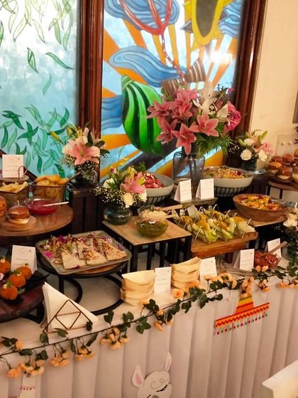 A vibrant and plentiful finger food buffet, perfect for a casual birthday or house party. The spread includes sliders, wraps, and other easy-to-eat items, decorated with a fun, festive garland.