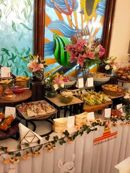 A vibrant and plentiful finger food buffet, perfect for a casual birthday or house party. The spread includes sliders, wraps, and other easy-to-eat items, decorated with a fun, festive garland.