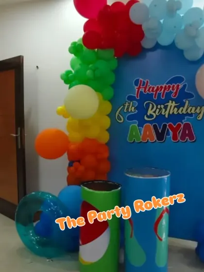 A fun pool party-themed backdrop, complete with a "wave" and colorful balloon accents. The prop cylinders are designed to look like soda cans.