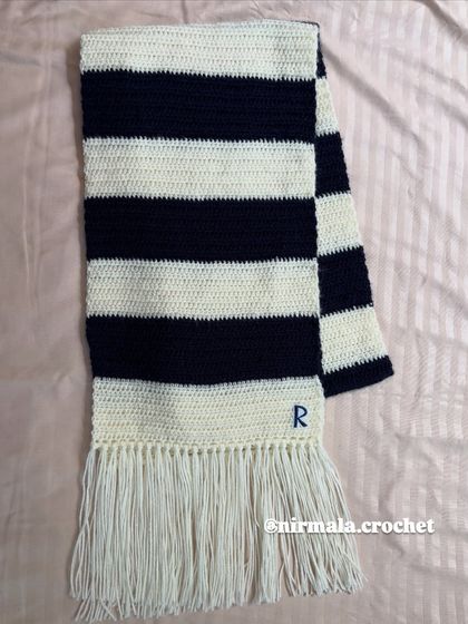 The finished custom initial muffler, laid flat to show the classic stripe pattern and personalized detail.