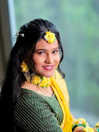 A happy bride ready for her Haldi ceremony. The makeup is light and glowy, with a bright lip color to match the festive mood.