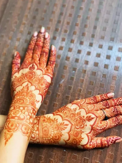 The back of the hands, showing a beautiful, mature henna stain in a Pakistani-style design.