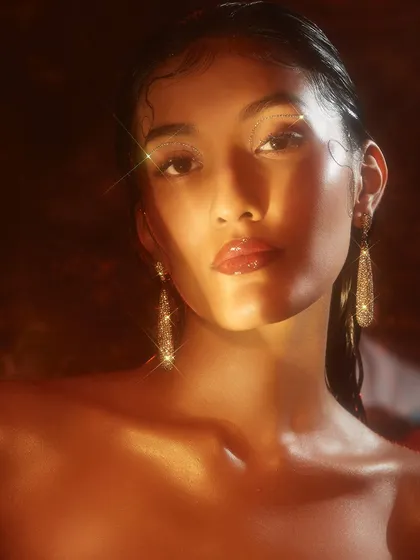A warm, glowing look with glossy skin and lips, captured with beautiful golden light that makes the model sparkle.