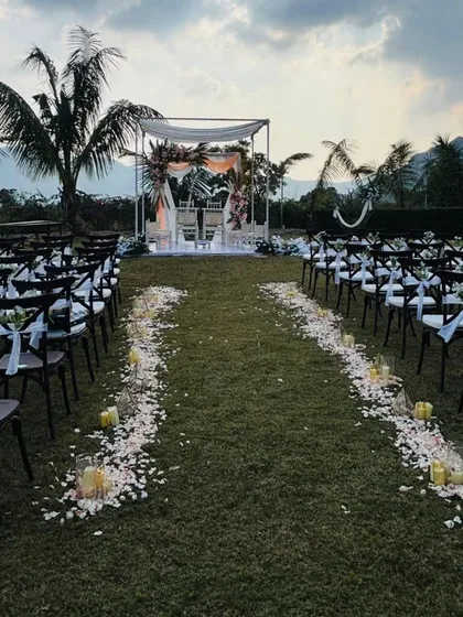 The wedding aisle is kept simple and beautiful with scattered white rose petals and candles. This minimalist approach ensures the focus remains on the couple and the ceremony itself.