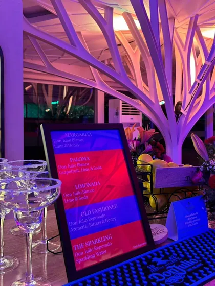 A close-up of the bar for the Don Julio event, featuring a custom menu of tequila cocktails like the Paloma and Margarita, with salt-rimmed glasses ready for service.