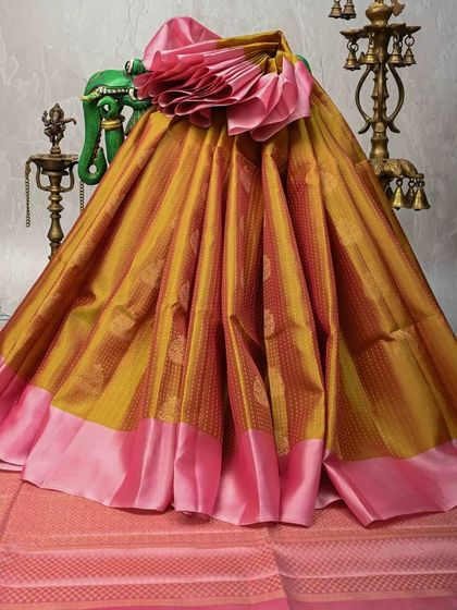 A unique dual-toned Kanjivaram in mustard yellow and pink. The body has a textured weave, and the plain pink border creates a beautiful, modern contrast.