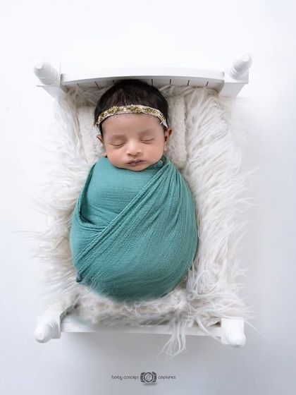 An overhead view of the newborn in the miniature white bed, showcasing the simple and classic appeal of this setup.