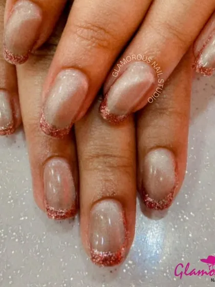 A simple yet glamorous look, these nails feature a sheer, shimmery base with a delicate red glitter French tip.