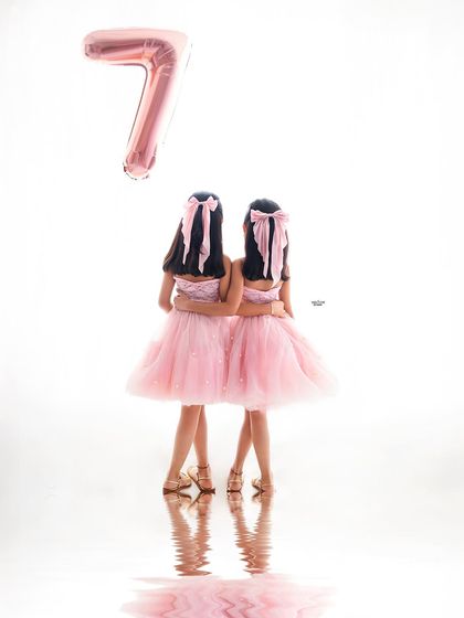 Turning seven with your best friend by your side. This creative shot captures these twin sisters on their birthday, with a single balloon marking their special age.