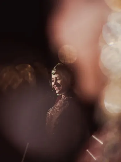 I often experiment with light and perspective to create artistic portraits. This shot captures the bride's joyful smile through a prism, creating a dreamy, bokeh-filled effect that turns a simple moment into a piece of abstract art.