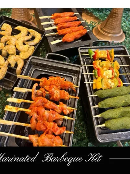 Perfect for winter evenings or barbecue lovers, our Marinated Barbecue Kit comes with a variety of pre-marinated vegetarian and non-vegetarian options. This image shows a selection including paneer tikka, chicken skewers, and seekh kebabs, ready for the grill.
